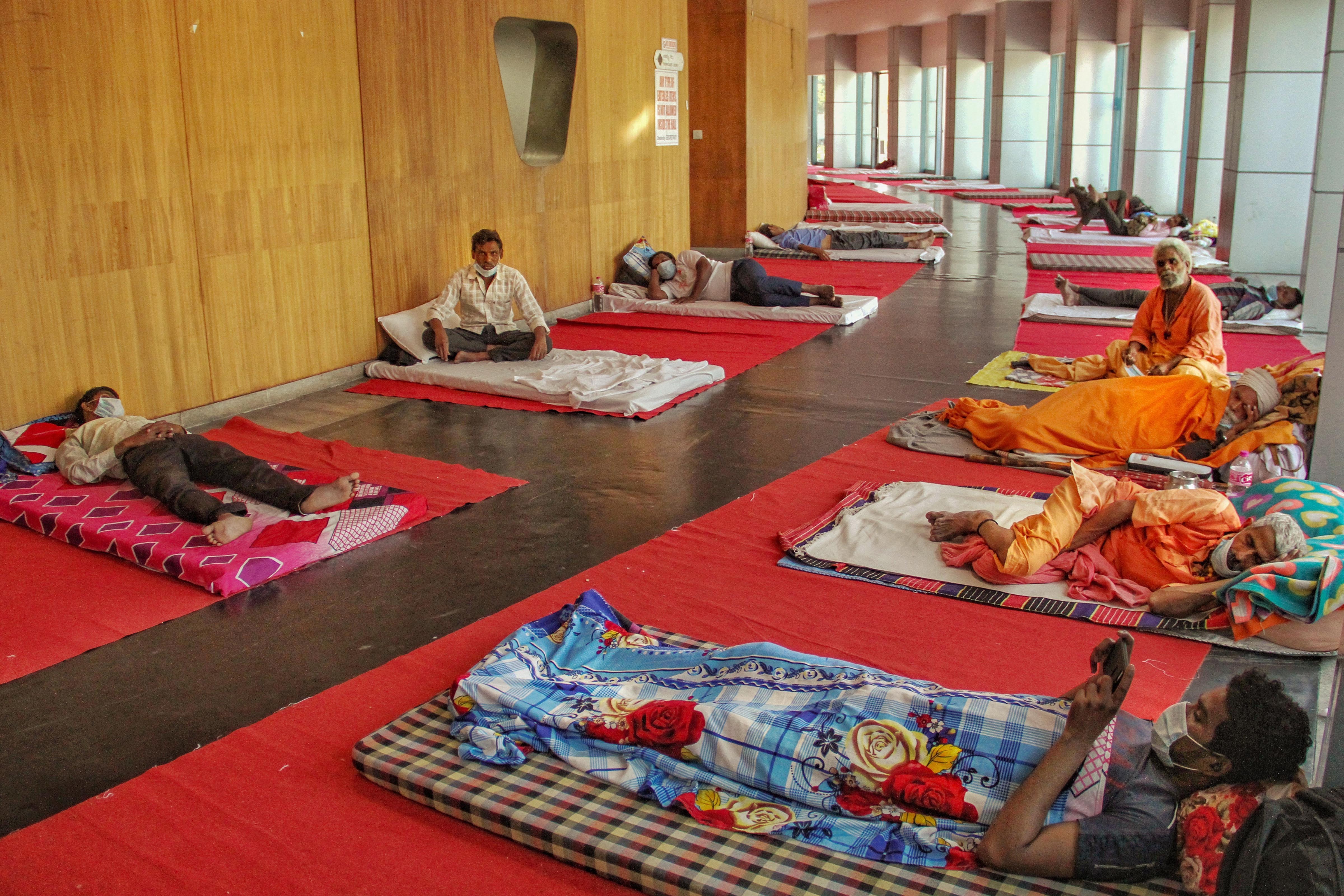 Migrant workers rest inside the Yamuna Sports Complex, which has been converted into a makeshift shelter during the ongoing Covid-19 lockdown, in New Delhi, Sunday, April 5, 2020
