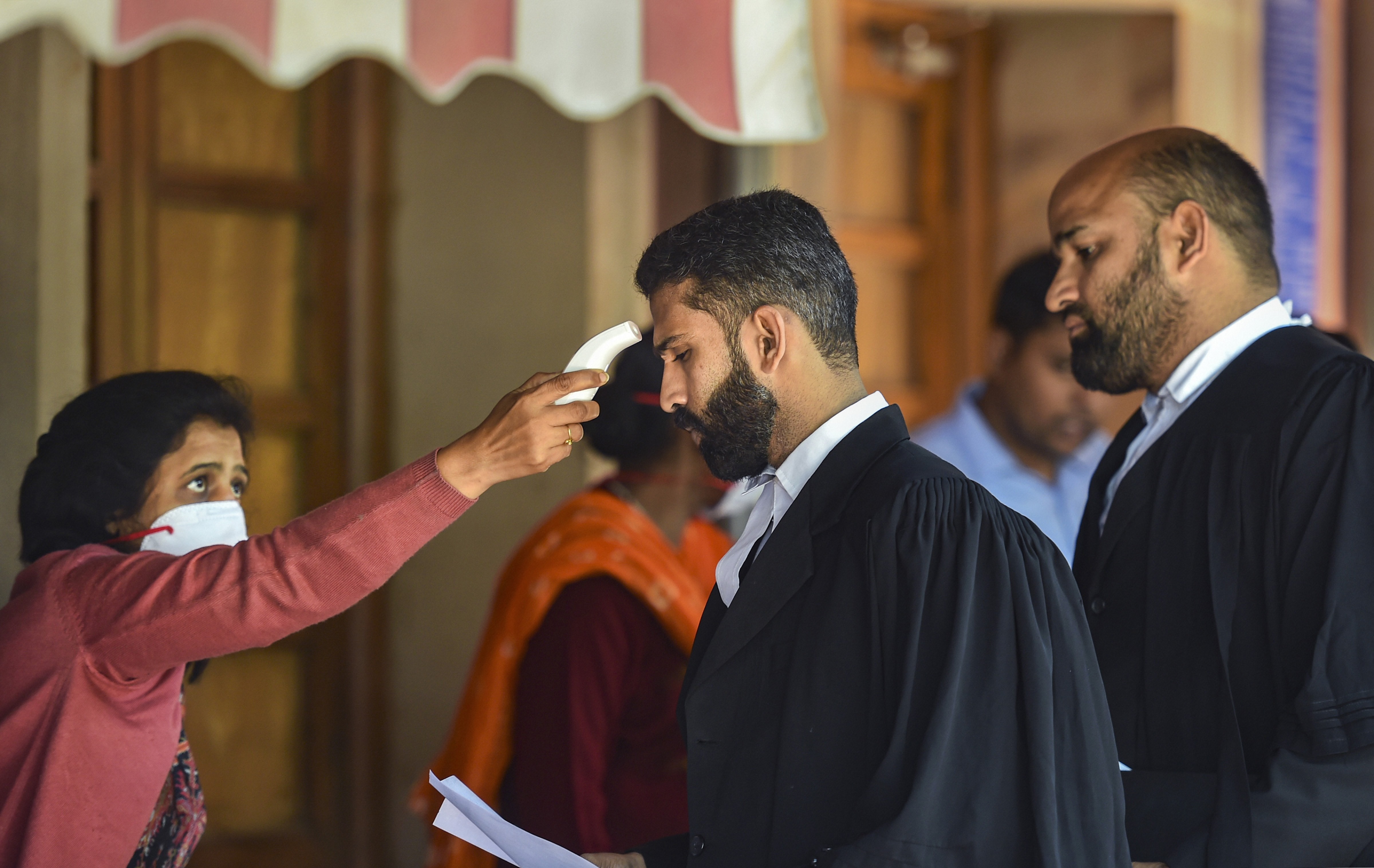 An official uses a thermal screening device on an advocate in the wake of deadly of coronavirus pandemic, at Supreme Court in New Delhi, Tuesday, March 17, 2020