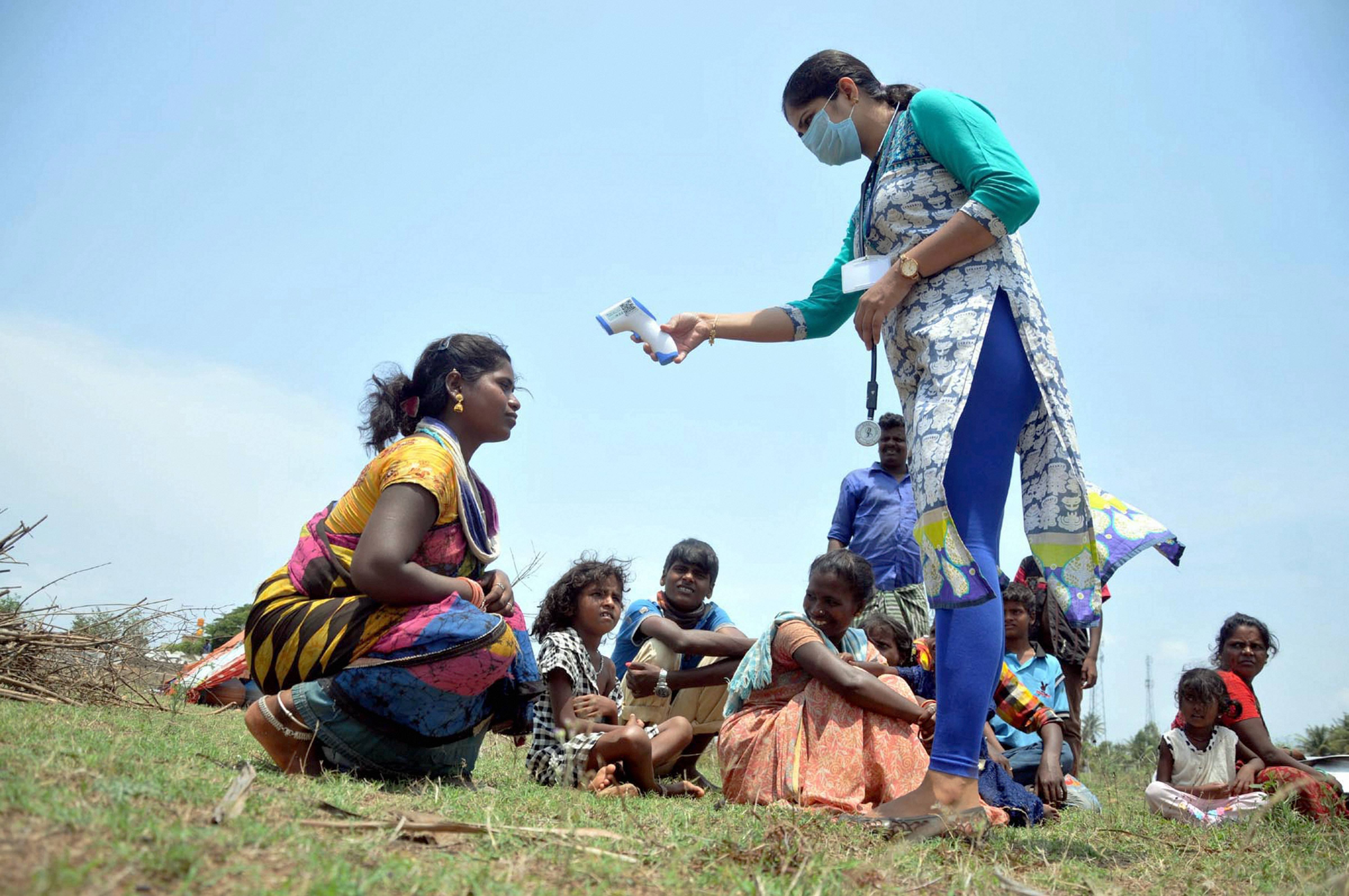 A medic checks the temperature of a migrant worker, during the nationwide lockdown to curb the spread of coronavirus, at Hiremagalur near Chikmagalur