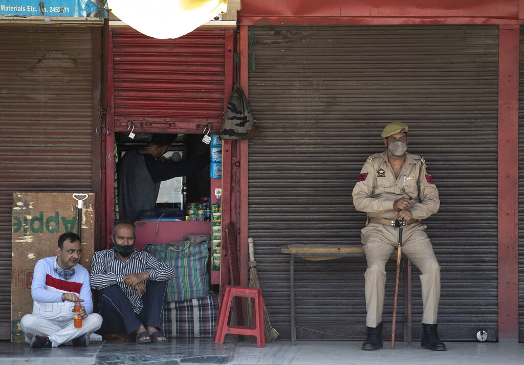 A policeman wearing a mask as a protection against the coronavirus keeps guard outside a half-closed shop in Srinagar, Tuesday, June 9, 2020.