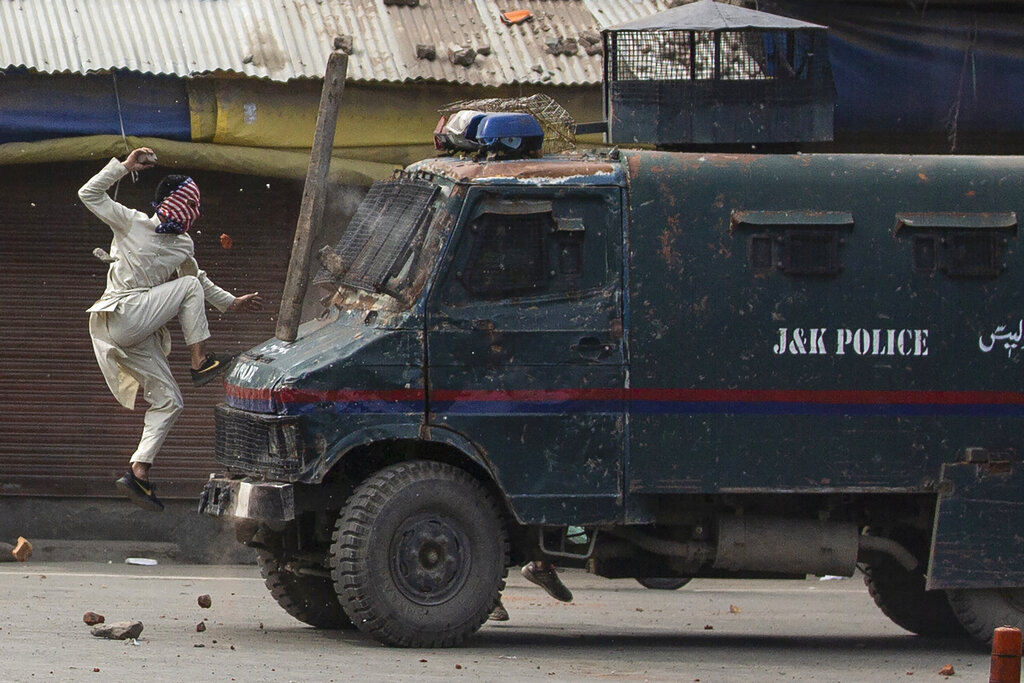 A masked Kashmiri protester jumps on the bonnet of an armored vehicle of Indian police as he throws stones at it during a protest in Srinagar, May 31, 2019. The image is part of the photo series that won the 2020 Pulitzer Prize for Feautre Photography.
