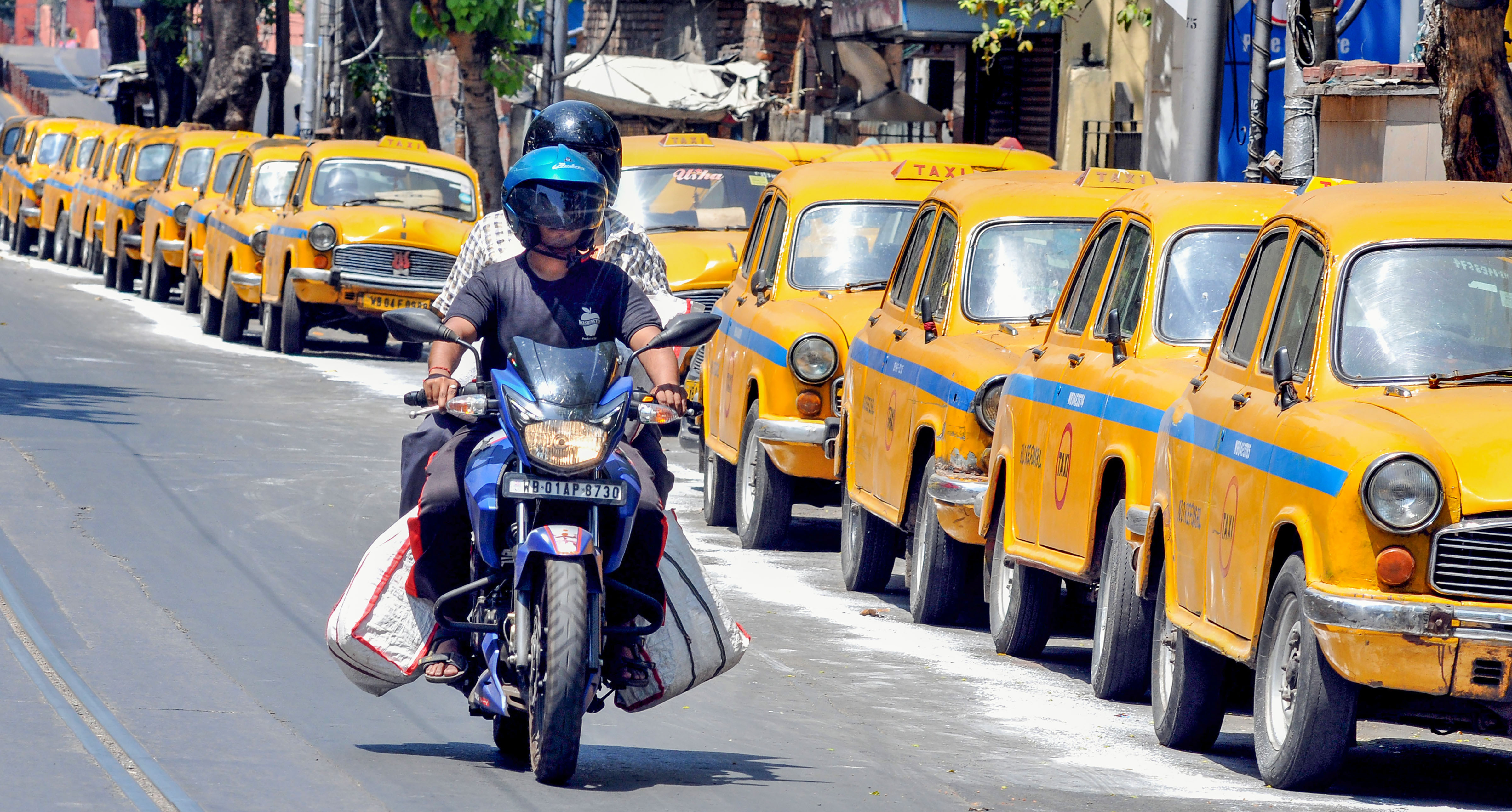 A biker rides past taxies parked along a road during the nationwide lockdown in wake of deadly coronavirus outbreak, in Calcutta, Monday, March 30, 2020