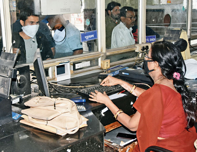 A railway employee and a passenger, both with faces covered, at Dhanbad station.