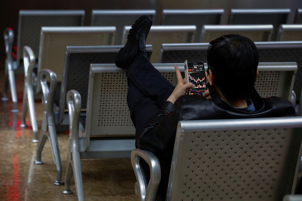 An investor checks stock prices using his smartphone in Beijing on December 19