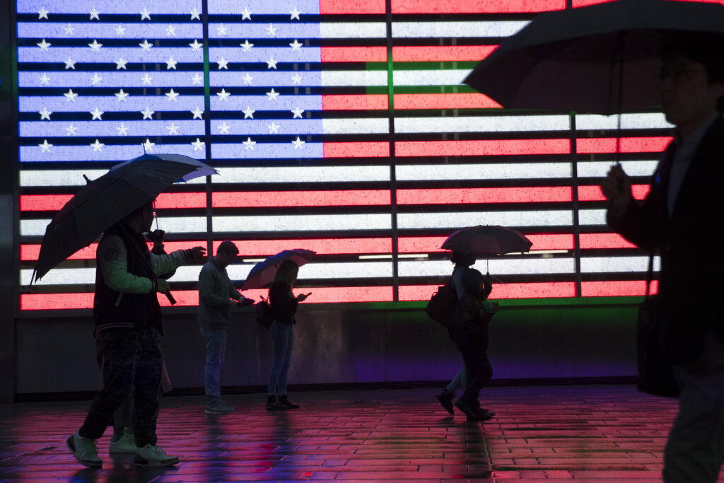 Visitors to New York's Times Square use umbrellas to shield themselves against the rain as they walk past the Armed Forces Recruitment Center. Before Election Day, politicians are expected to spend more than $1 billion to pelt voters with millions of cheap online ads, which can be tailored to a voter's most personal details — down to one household or even a single individual.
