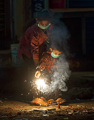 Indians light fire crackers wearing masks to fight pollution as they celebrate Diwali, the festival of lights in Hyderabad, India, Wednesday, Nov. 7, 2018. India's top court recently ruled that only less polluting firecrackers should be manufactured and sold.