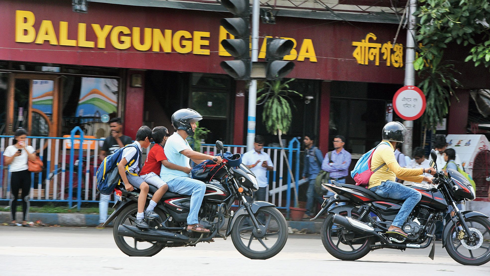 Another man riding a bike near Ballygunge Phari with two boys on the pillion without the headgear.