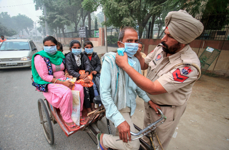 A police constable in Bathinda, Punjab, distributes masks to people in the street on Saturday, November 10, to protect them from the smog caused by the burning of crop stubble in fields in the region.