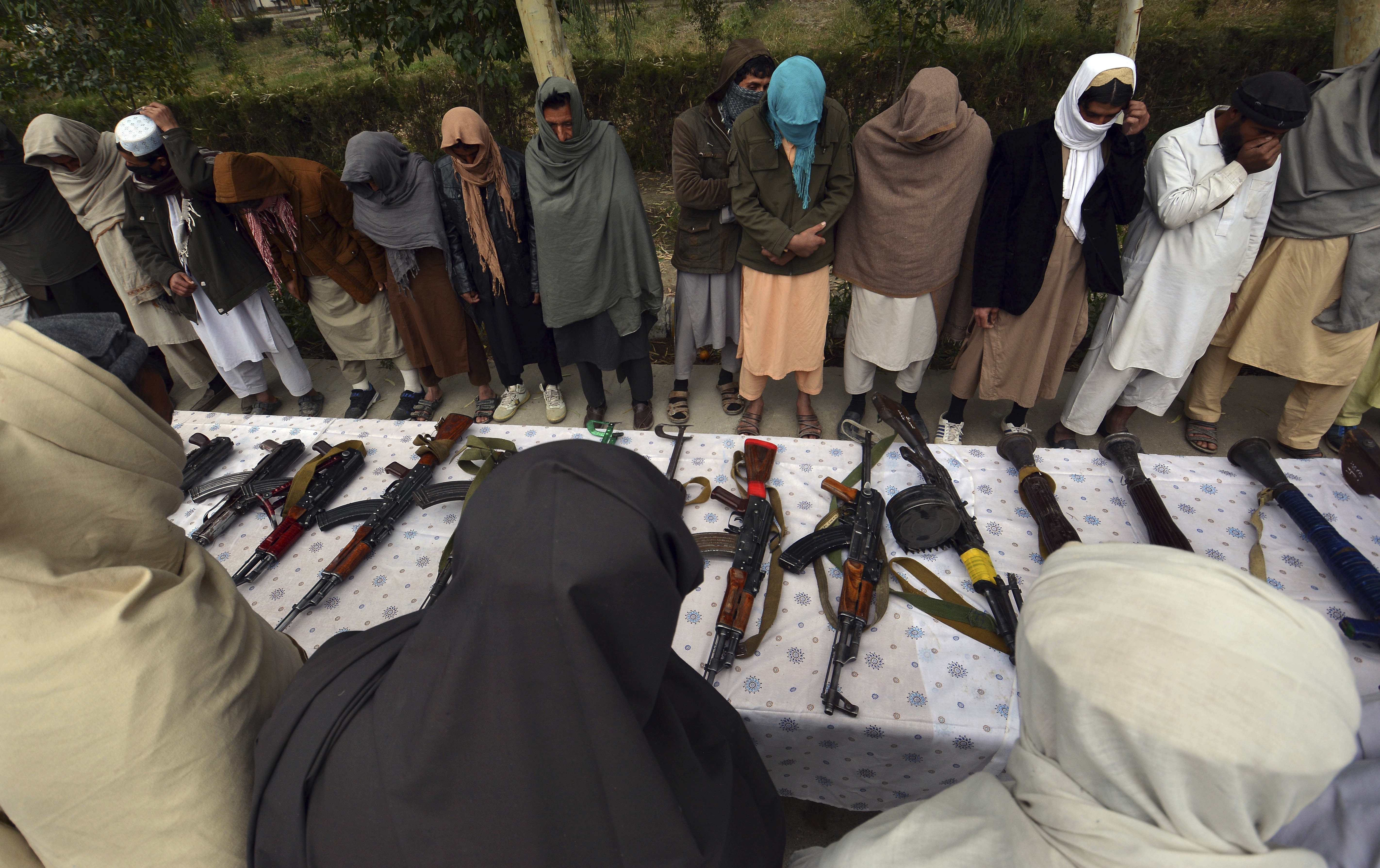 Former Taliban militants stand near their weapons at a ceremony with the Afghan government in Jalalabad, Afghanistan, on November 22, 2018. About 54 former militants from Jalalabad province handed over their weapons as part of of a peace-reconciliation program