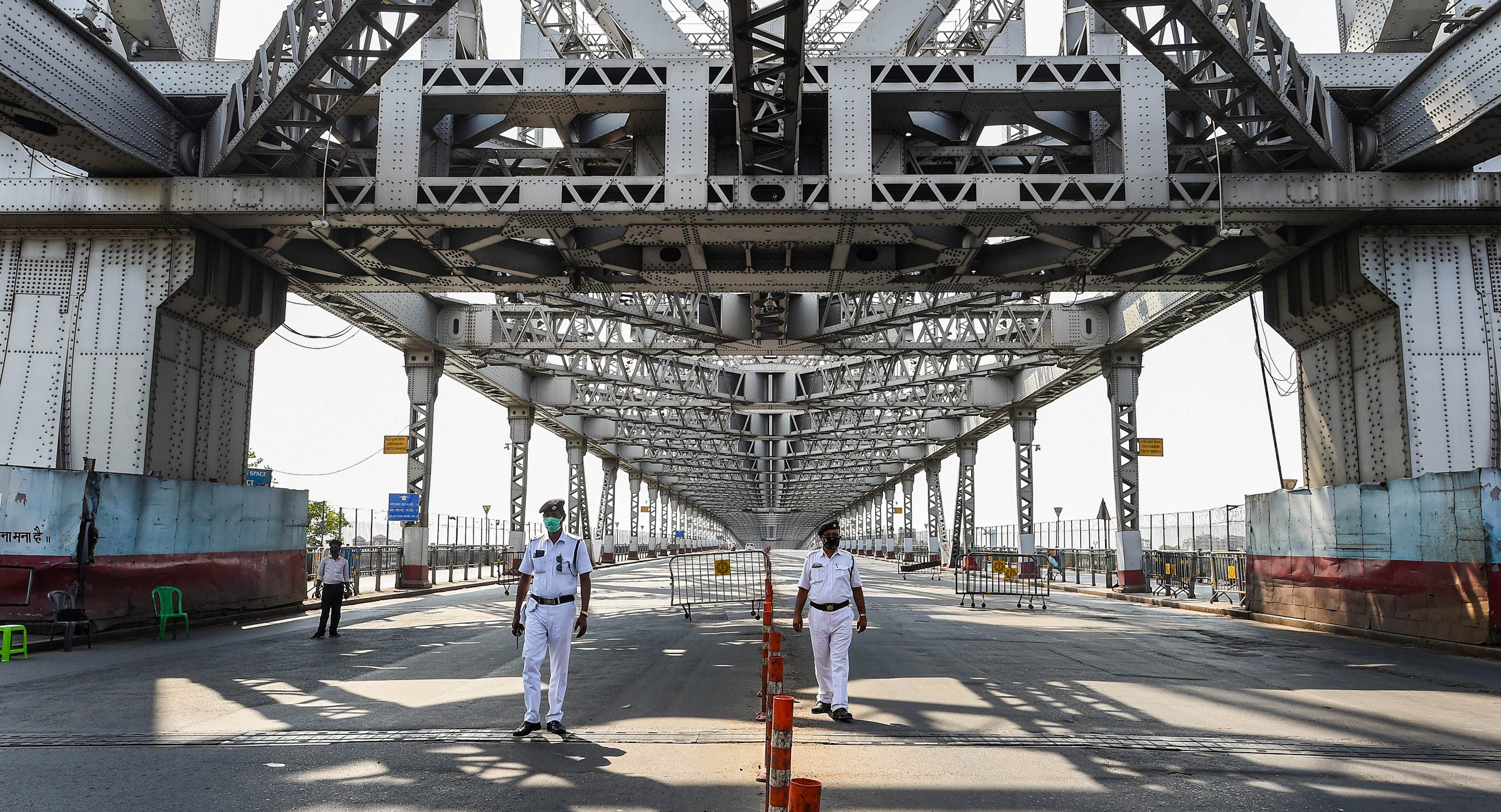 Traffic policemen guard the deserted Howrah Bridge during the nationwide lockdown imposed to curb the spread of novel coronavirus, in Calcutta