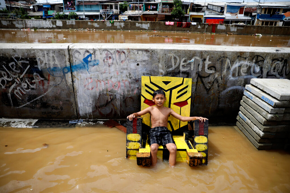 A young boy sits on a chair in a flooded neighbourhood in Jakarta on January 2