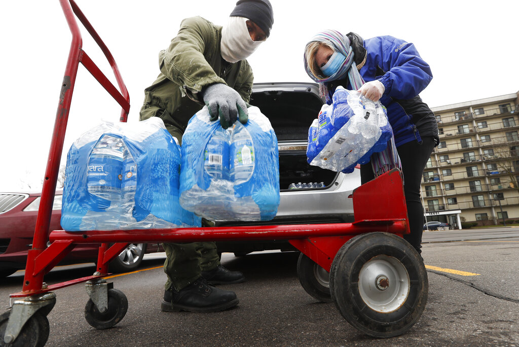 Rabbi Yosef Chesed, left, helps unload bottled water being donated from Lorie Lutz, right, at the Brightmoor Connection Food Pantry in Detroit, Monday, March 23, 2020. The global coronavirus pandemic has brought water shutoffs in Detroit and in communities across the nation into sharp focus again amid a crucial time.