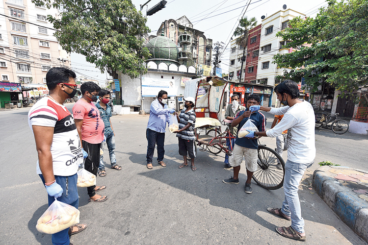 Five residents of Picnic Garden distribute essential items like rice, dal, potatoes and oil to cycle rickshaw drivers and some poor people in their area and in Ballygunge