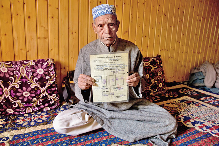 Ghulam Mohammad Zargar, an elderly Kashmiri, shows his domicile document, locally known as “State Subject”, which was held only by permanent residents of the state. Zargar said that with the abrogation of Article 370, the document 
as well as his Kashmiri identity were gone.