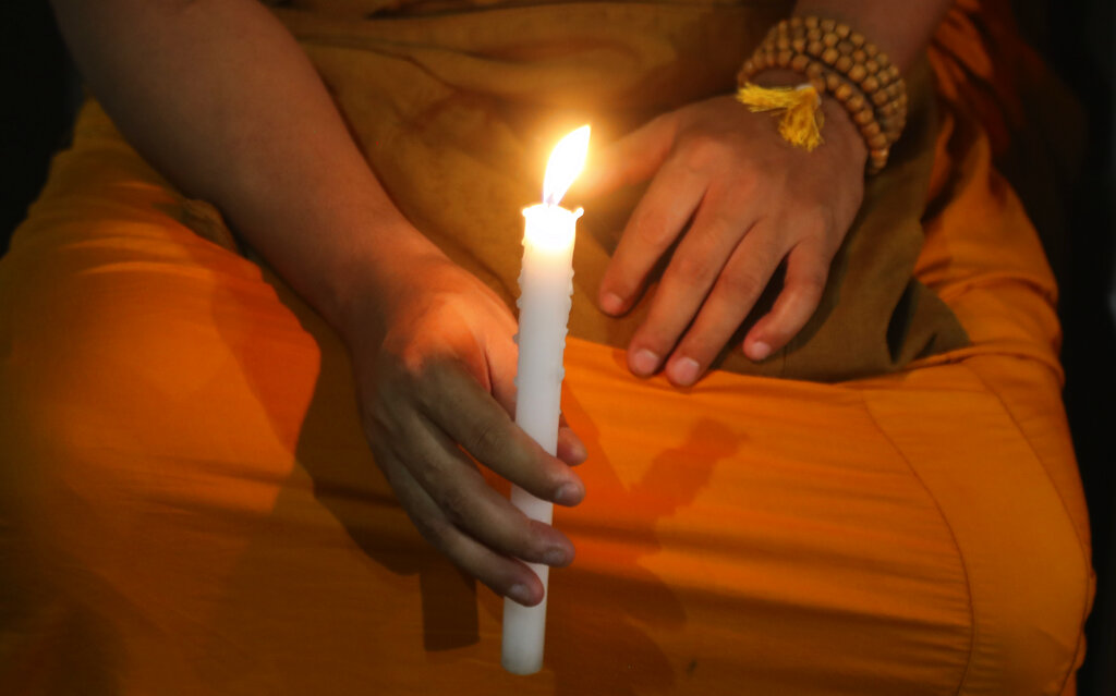 A Buddhist monk holds a candle and prays for a deadly virus outbreak to stop spreading, in Mumbai, on Thursday,