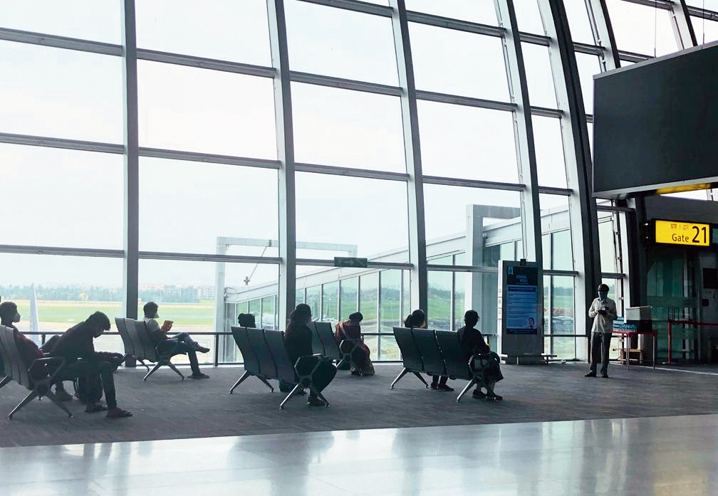At the boarding gate, passengers maintain social distance by keeping one seat between them vacant