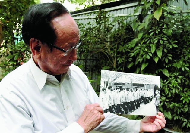 Tran Trong Duyet, the former director at the Hoa Lo prison in Hanoi that was dubbed the “Hanoi Hilton” and where McCain was held, holds on January 3, this year, a photo of himself with US prisoners of war at the jail.
