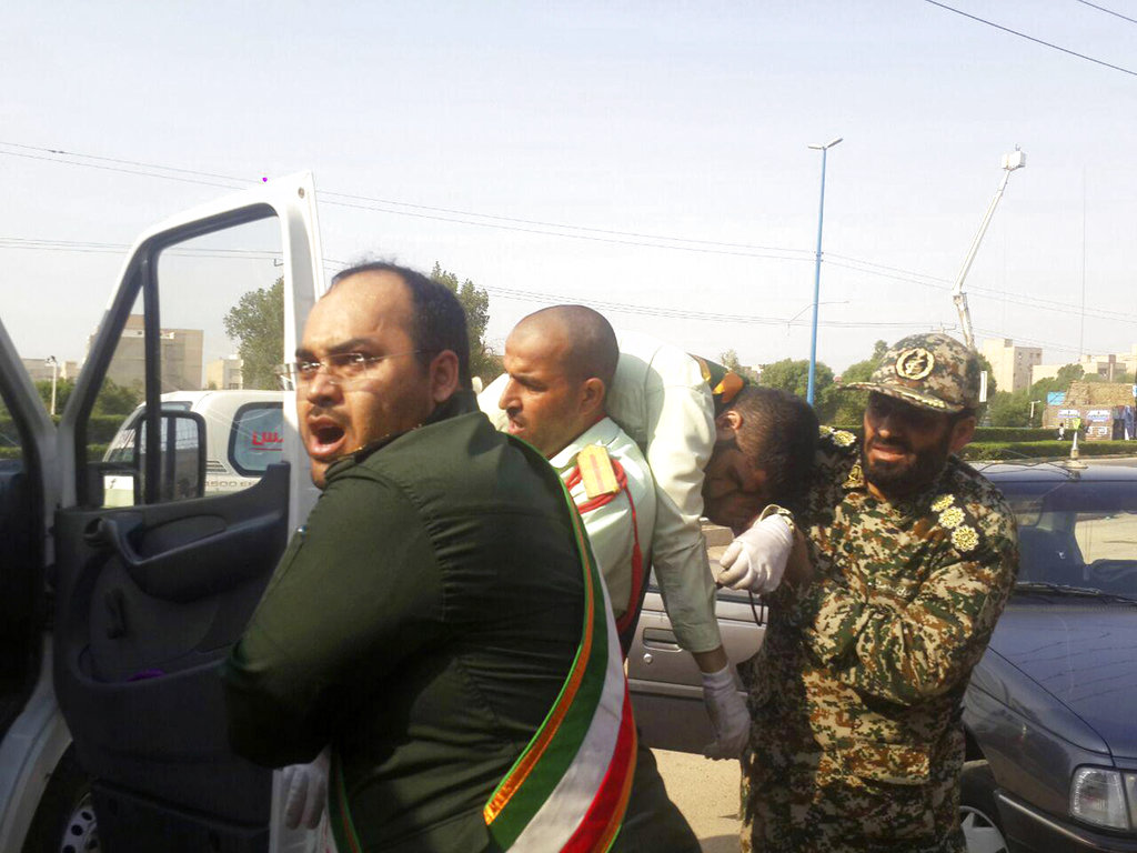 In this photo provided by the Iranian Students' News Agency, ISNA, Revolutionary Guard members carry a wounded comrade after a shooting during their parade.