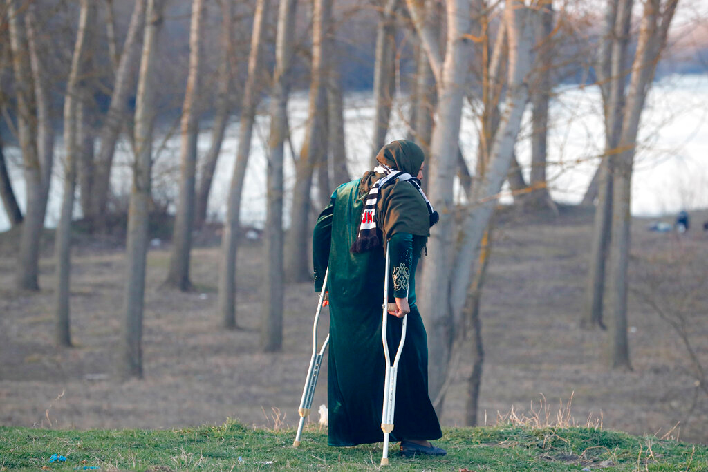 A migrant woman uses crutches while walking to Greece near Doyran, Turkey, on March 1