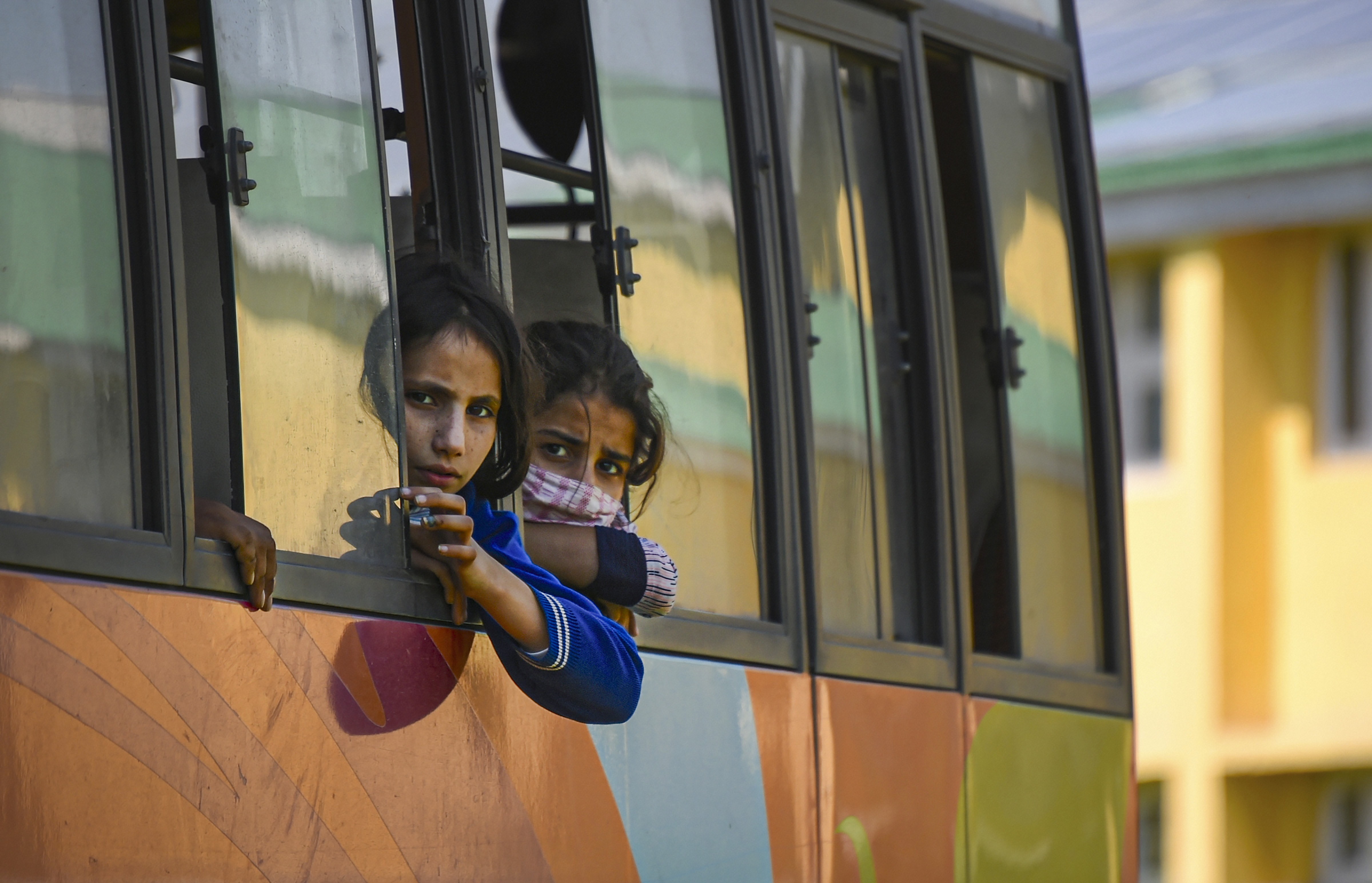 Girls, who were stranded along with their families in Haryana, look through the window of a bus after arriving at Tourist Reception Center, during the nationwide Covid-19 lockdown, in Srinagar, Friday, May 15, 2020.