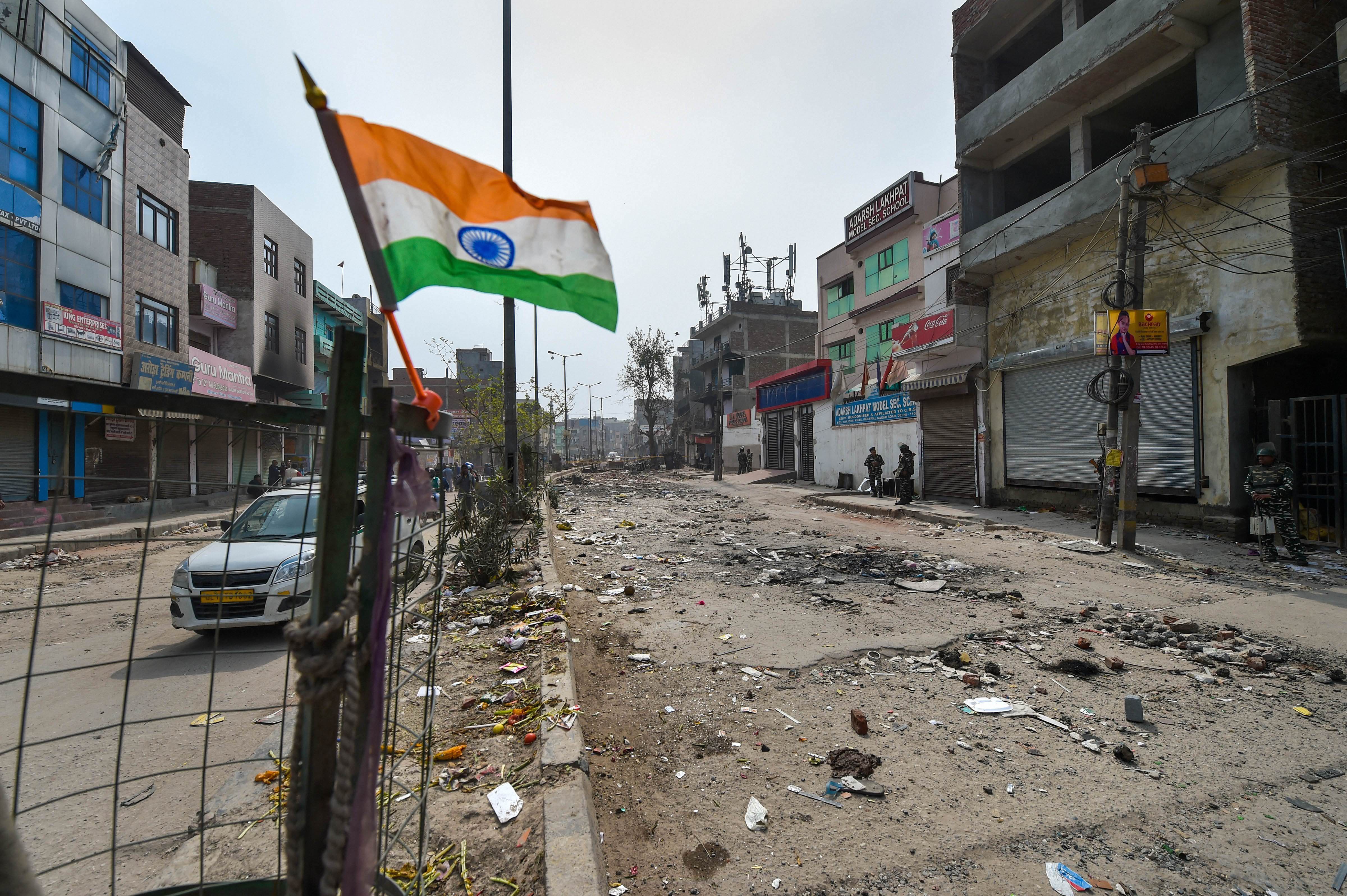 An Indian flag is seen on a fence overlooking a deserted market area of riot-affected part of northeast Delhi, Friday, February 28, 2020
