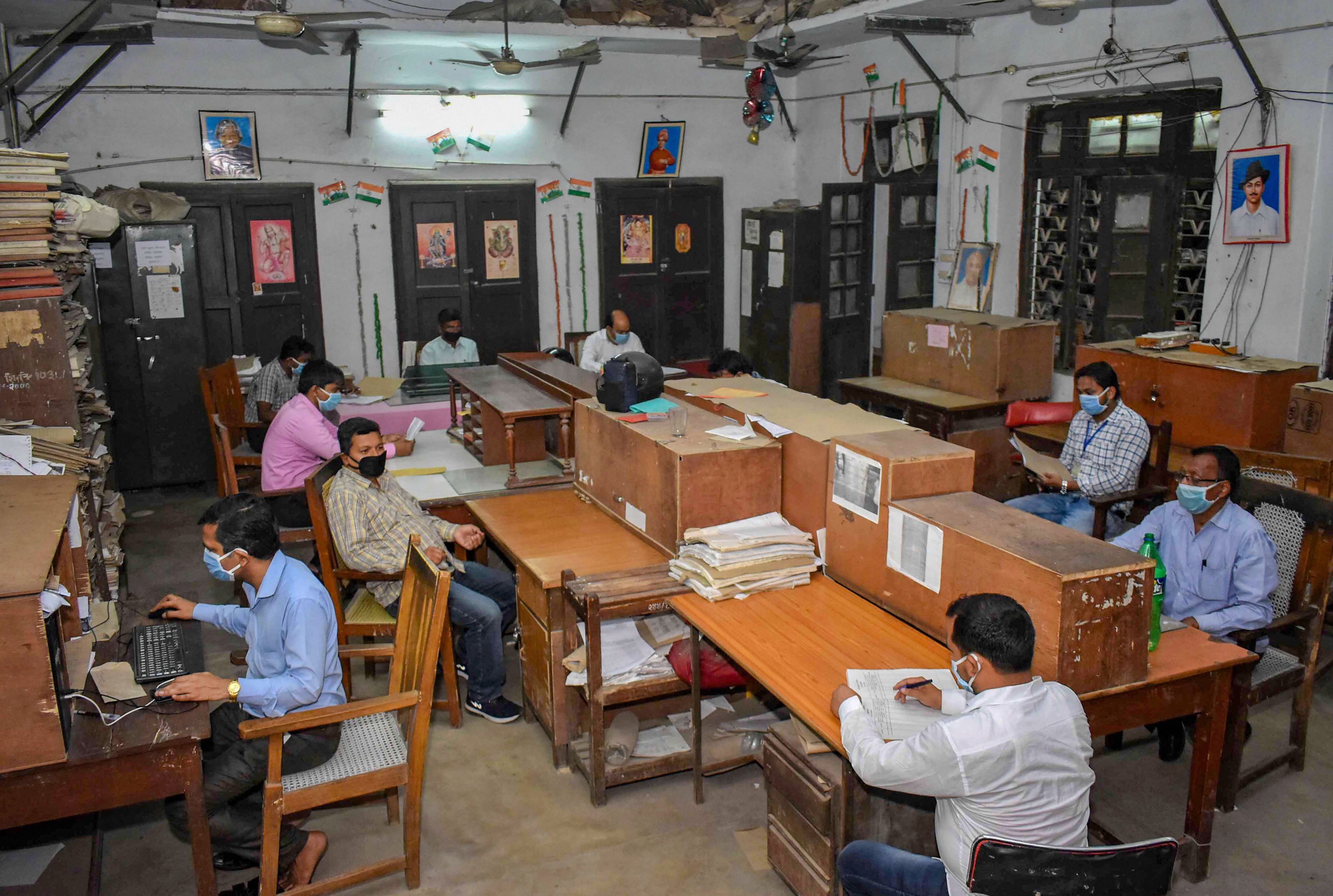 Employees wearing face masks practice social distancing at an office during the nationwide lockdown imposed to curb the spread of coronavirus, in Prayagraj, Monday, April 20, 2020