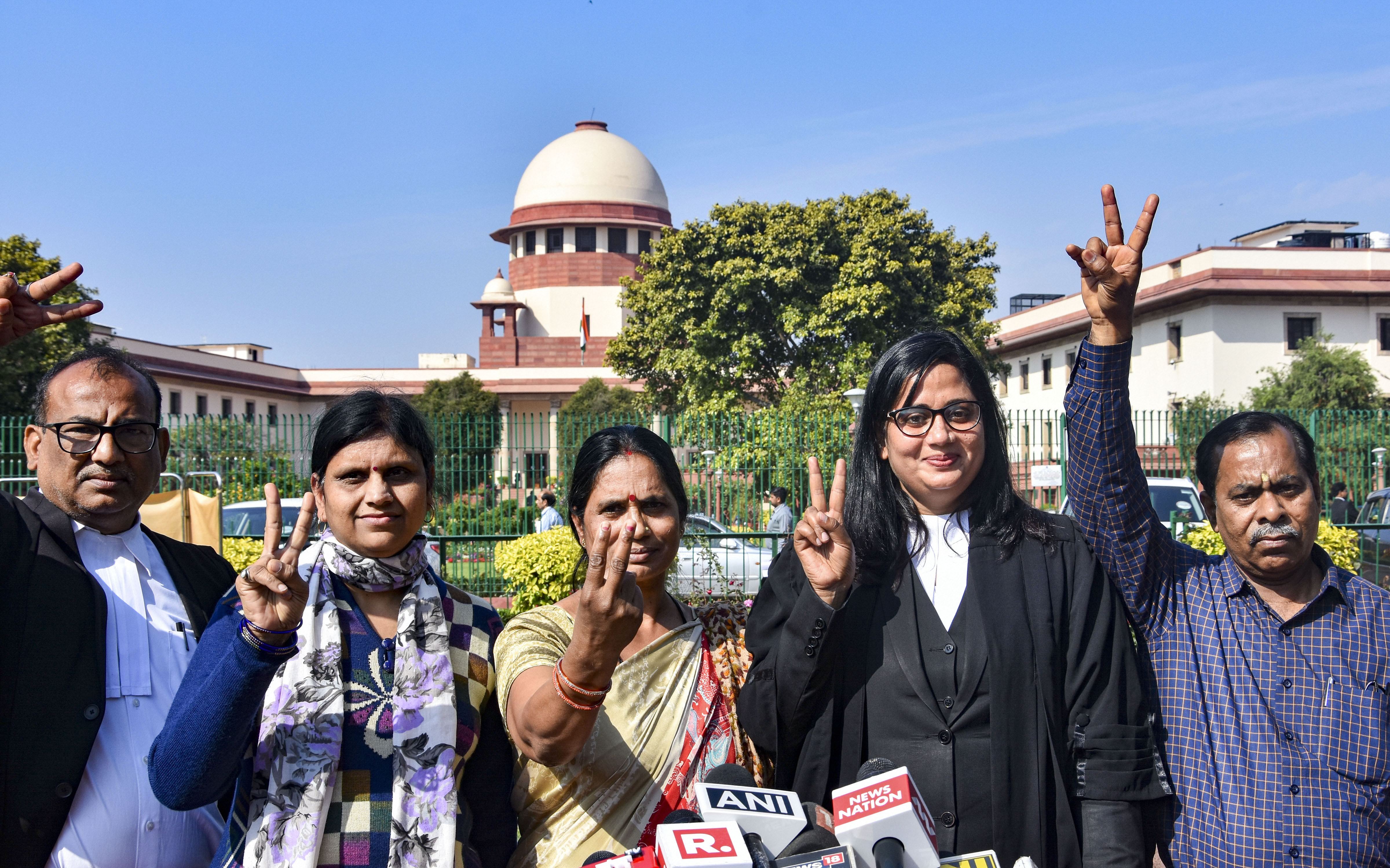 2102 Delhi rape and murder case victim's mother and father flash the victory sigh while speaking to media personnel outside Supreme Court in New Delhi, Monday, March 16, 2020
