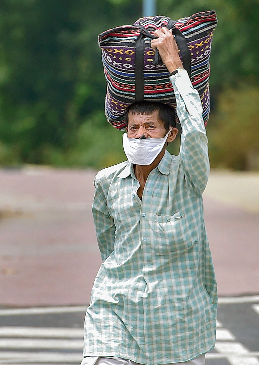 A migrant worker walks along a road near Akshardham Temple in New Delhi on his way to his home on Tuesday.