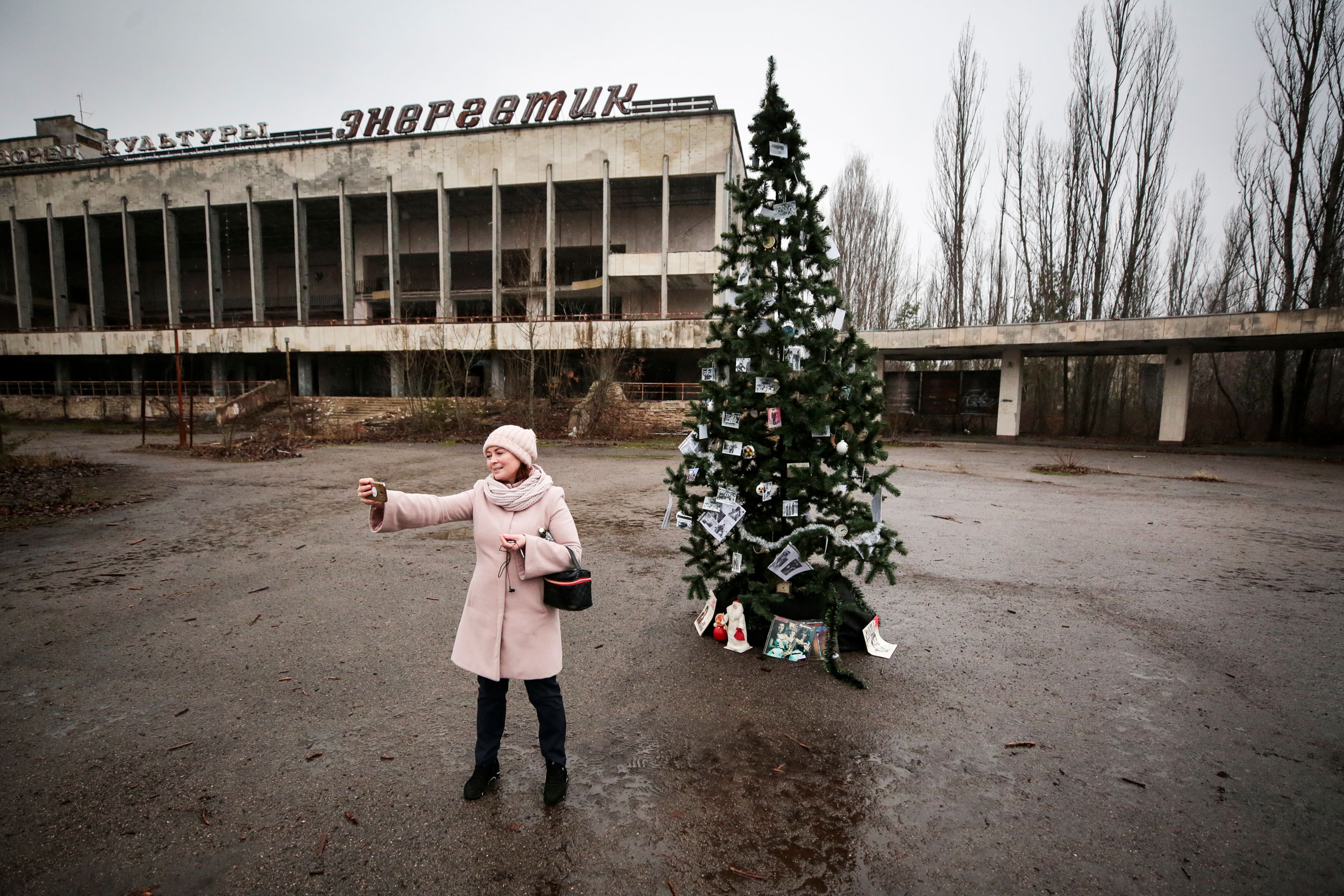 In this Wednesday, December 25, 2019, photo, a former resident records herself by a Christmas tree in a central square of the abandoned city of Pripyat, not far of the Chernobyl nuclear power station, Ukraine.