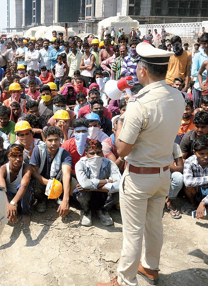 Police appeal to the protesting migrant workers, demanding to be allowed to return to their home states, to maintain calm at the construction site in Surat on Tuesday. 