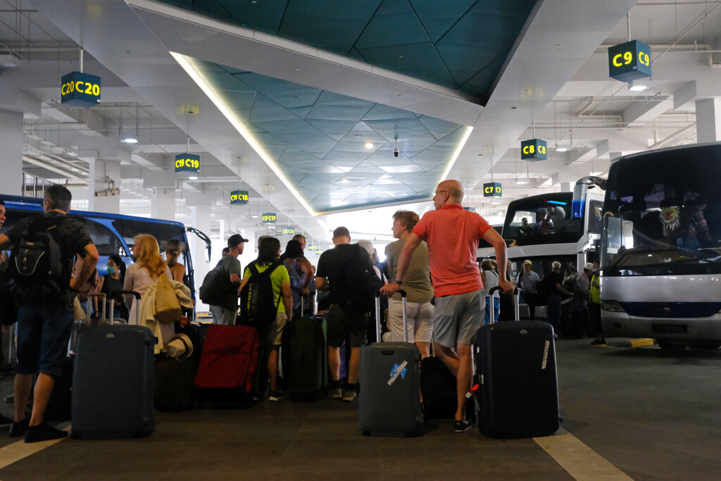 Passengers of the Costa Fortuna cruise ship are seen with their luggages as they waited to board buses at the Marina Bay Cruise Center Singapore on Tuesday, March 10, 2020.