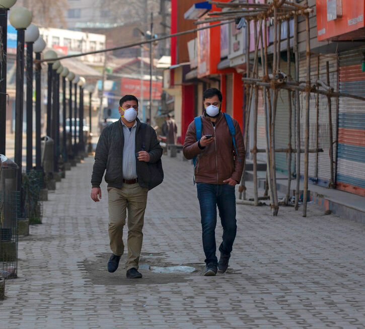 Kashmiri men wearing protective masks walk past closed shops as restrictions continued on the movement of people after the first person in the region was tested positive Tuesday for COVID-19, in Srinagar on Friday, March 20, 2020. 