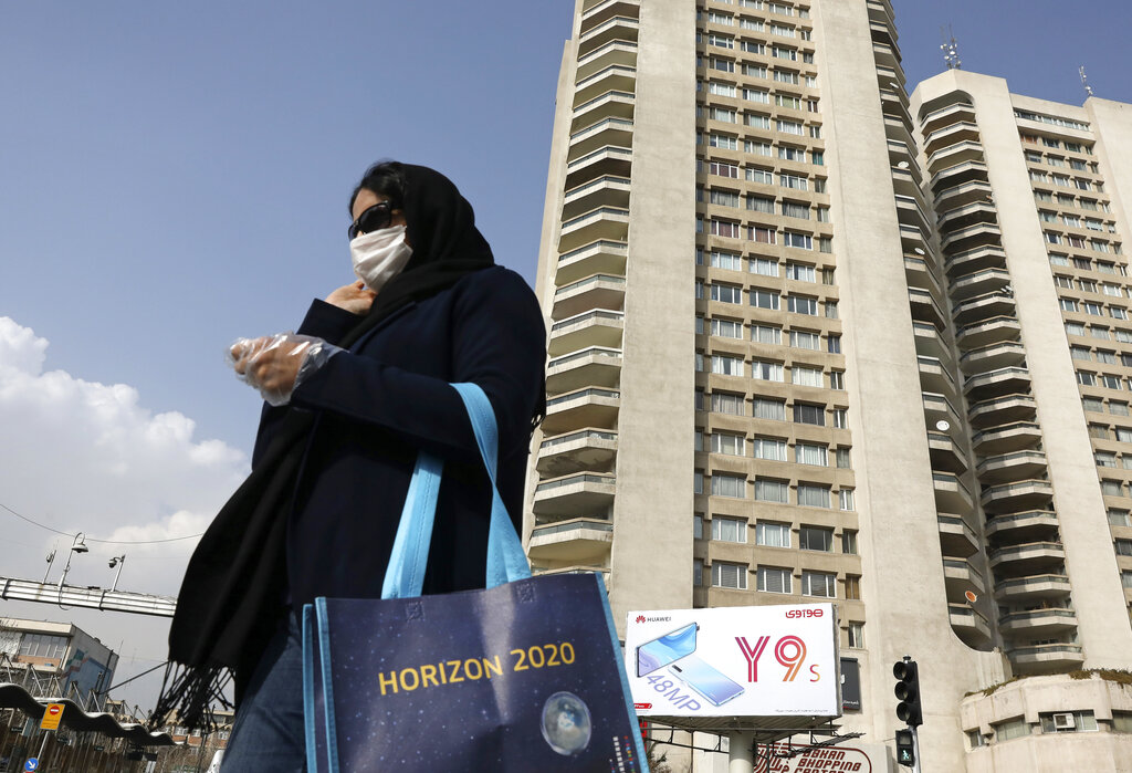 A pedestrian wearing a face mask crosses a street in northern Tehran on Sunday