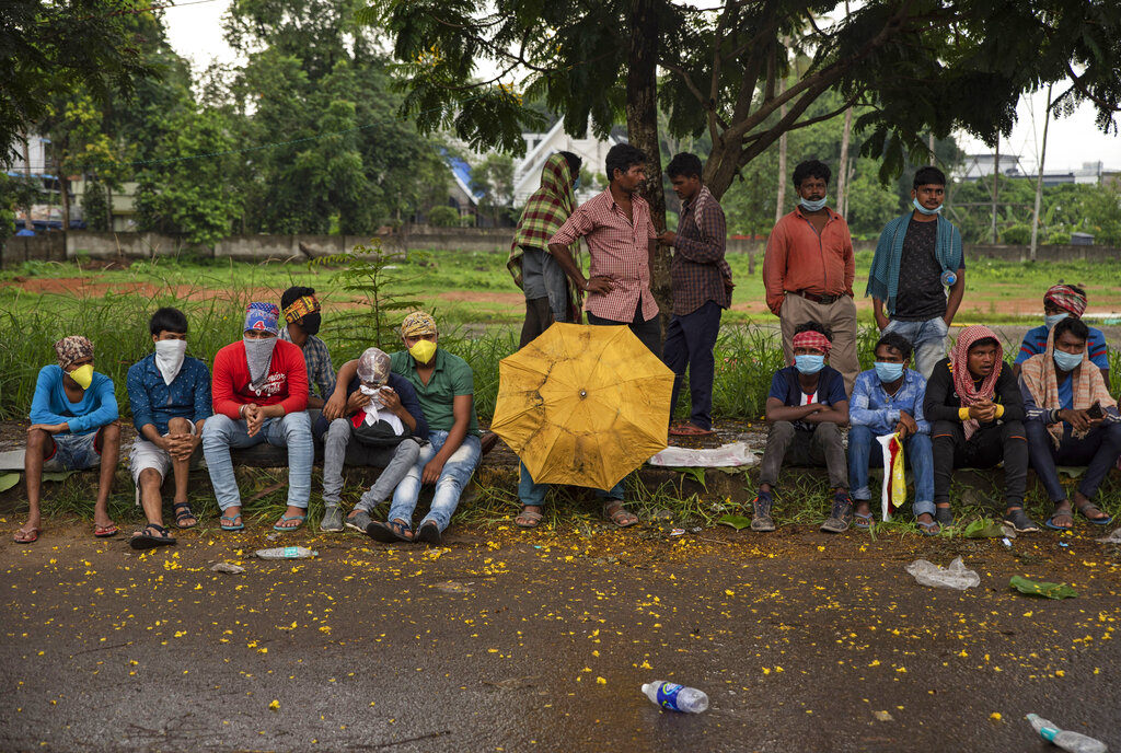 Migrant workers from eastern West Bengal state wait after queueing up overnight on a roadside pavement to register for home bound trains in Kochi, Wednesday, June 3, 2020.