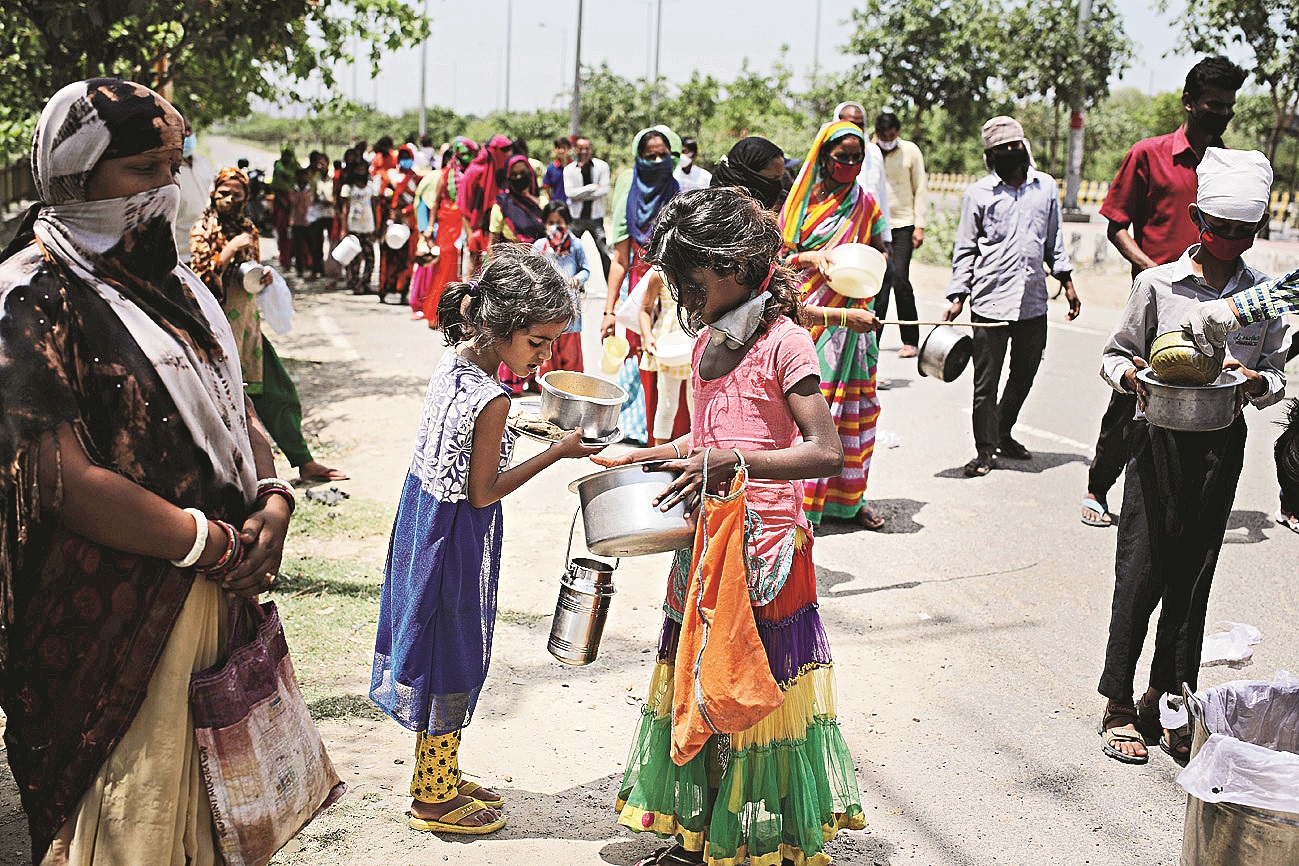 Two young girls look at the food they received from local authorities during a distribution drive for people left jobless due to continuous lockdown, in Noida, May 4, 2020.