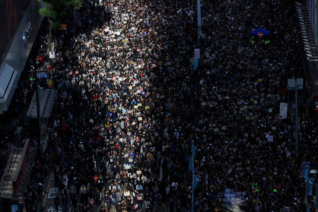 A beam of sunlight shines on pro-democracy protesters as they march on a street in Hong Kong on Sunday. Thousands of people took to the streets of Hong Kong in a march seen as a test of the enduring appeal of an anti-government movement about to mark a half year of demonstrations.