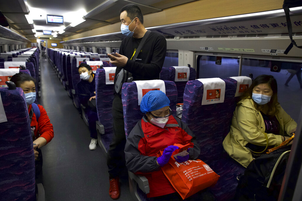 Passengers wearing face masks to protect against the spread of new coronavirus board the first high-speed train to leave Hankou train station after the resumption of train services in Wuhan in central China's Hubei Province