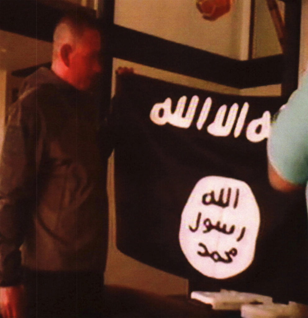 In this undated file image taken from FBI video Ikaika Kang holds an Islamic State group flag after allegedly pledging allegiance to the group at a house in Honolulu.