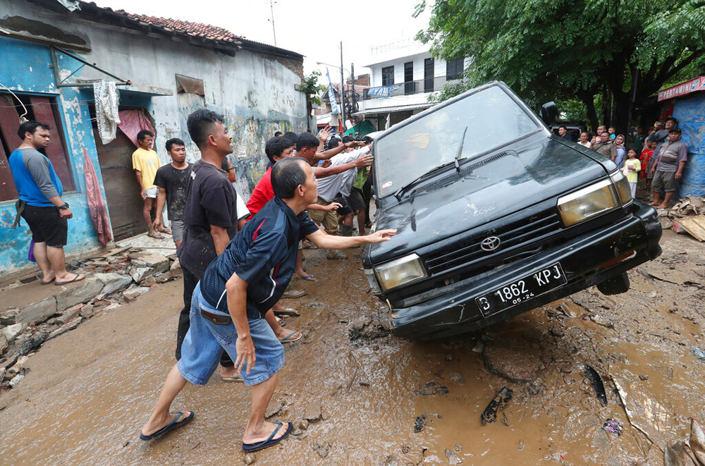 Residents move the wreckage of cars that were swept away by flood in Bekasi, West Java, on January 3