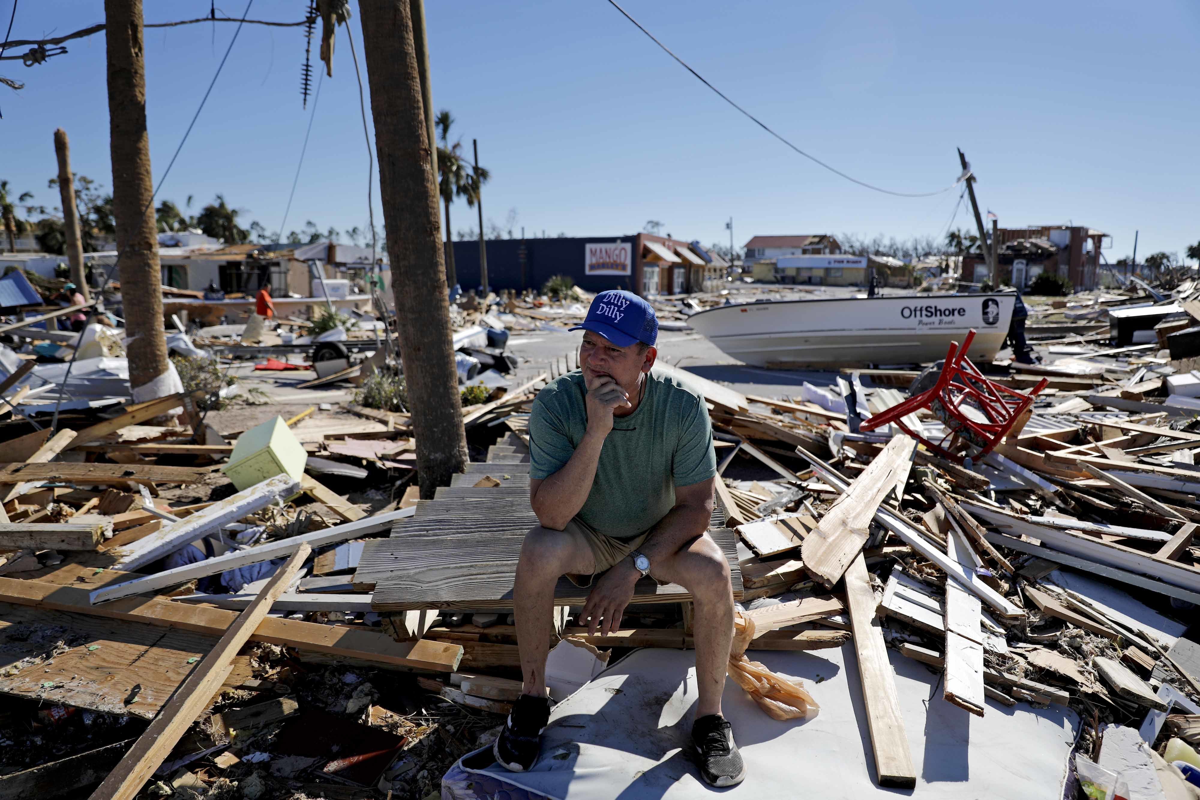 A man sits on a debri pile near his home which was destroyed by hurricane Michael in Mexico Beach, Florida
