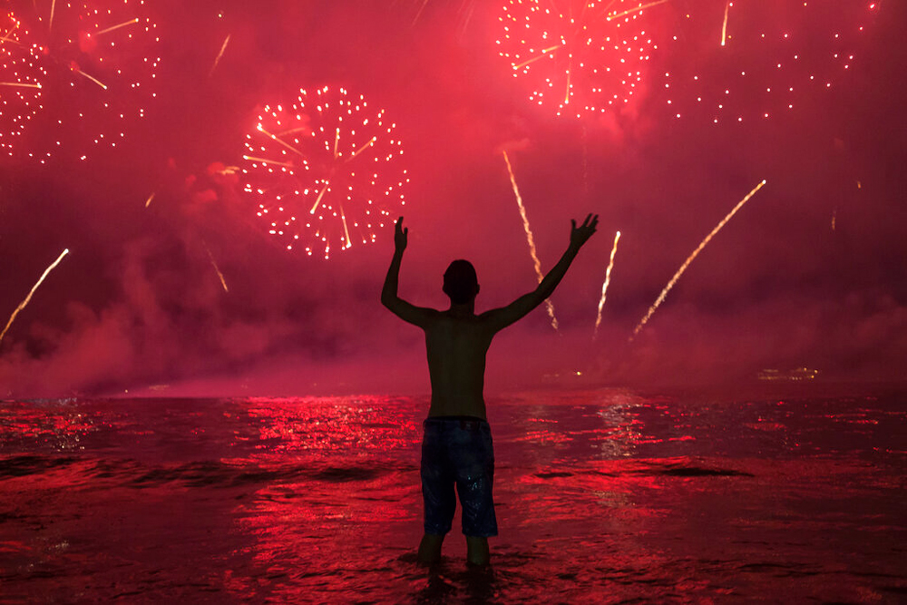 A man watches fireworks exploding over Copacabana Beach during the New Year's celebrations in Rio de Janeiro, Brazil, on January 1