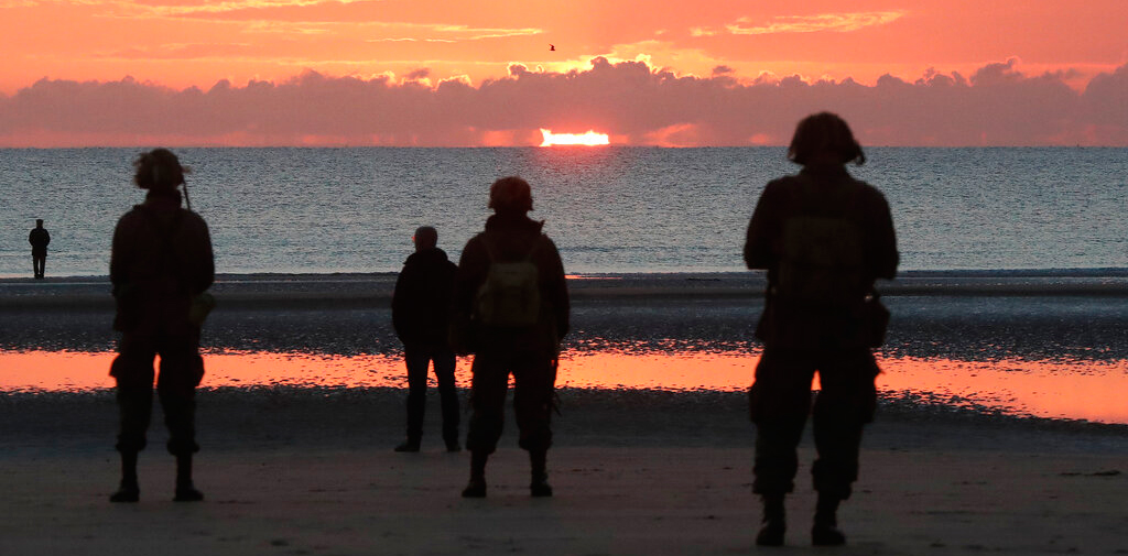 World War II re-enactors stand on Omaha Beach, in Normandy, France, at dawn on Thursday, June 6, 2019 during commemorations of the 75th anniversary of D-Day.