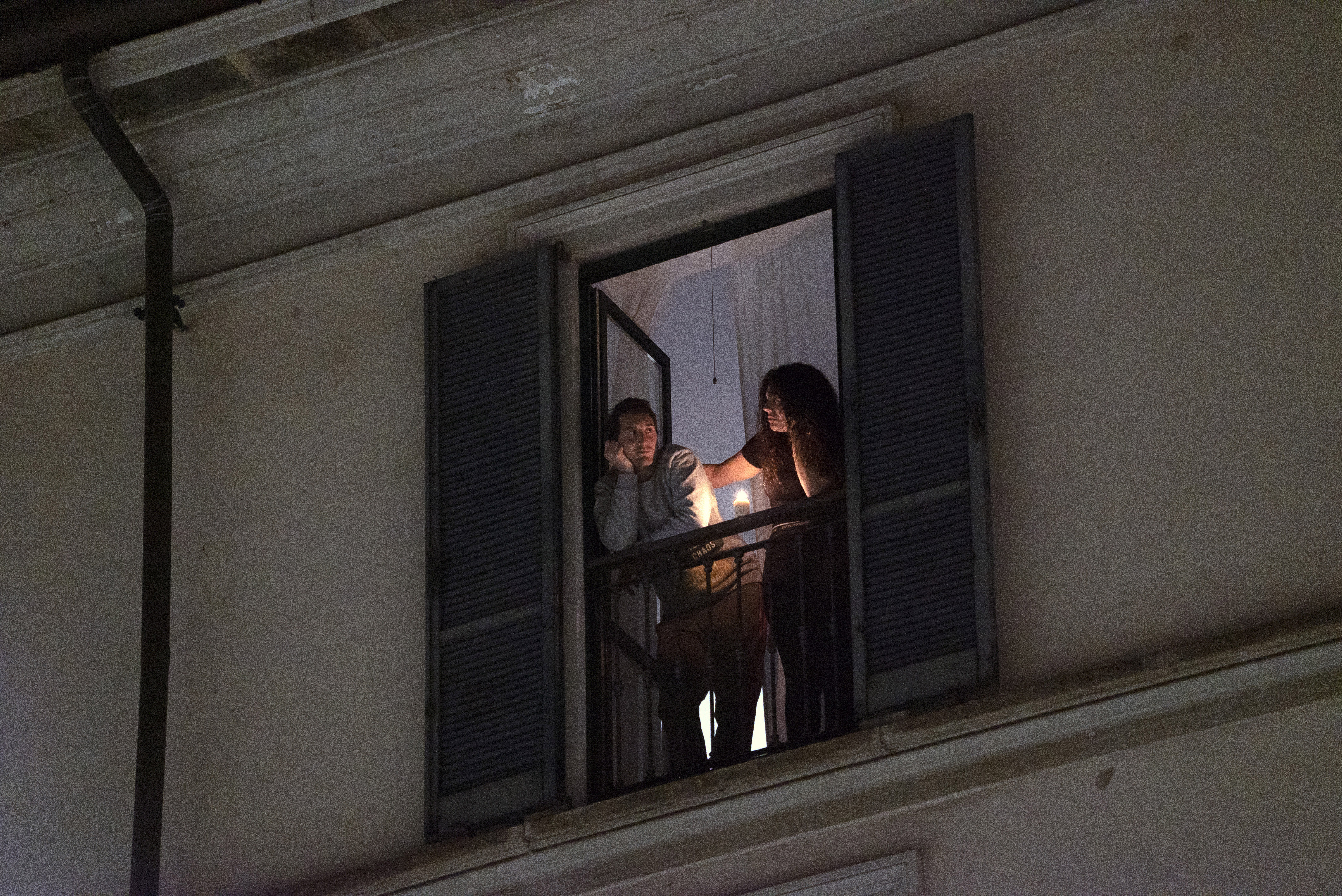 Residents look out from their balcony in Milan, March 15, 2020. Bodies are piling up in Italy as traditional funeral services are illegal throughout the country now, part of the national restrictions against gatherings and going out that have been put in place to try to stem the spread of Europe’s worst outbreak of the coronavirus.
