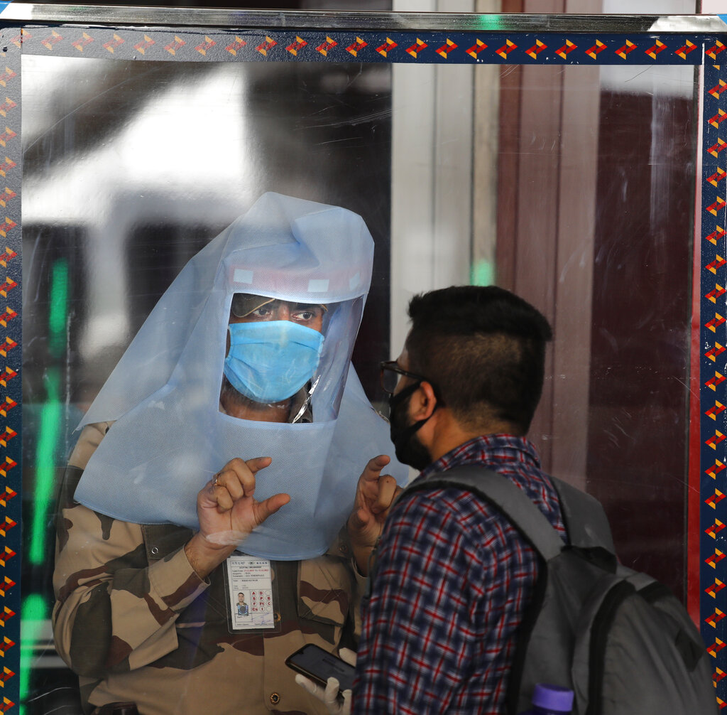 A security person standing behind a glass shield checks the identity of a passenger at the airport as domestic flights resume operations after nearly two-month lockdown amid the Covid-19 pandemic in New Delhi, Monday, May 25, 2020.
