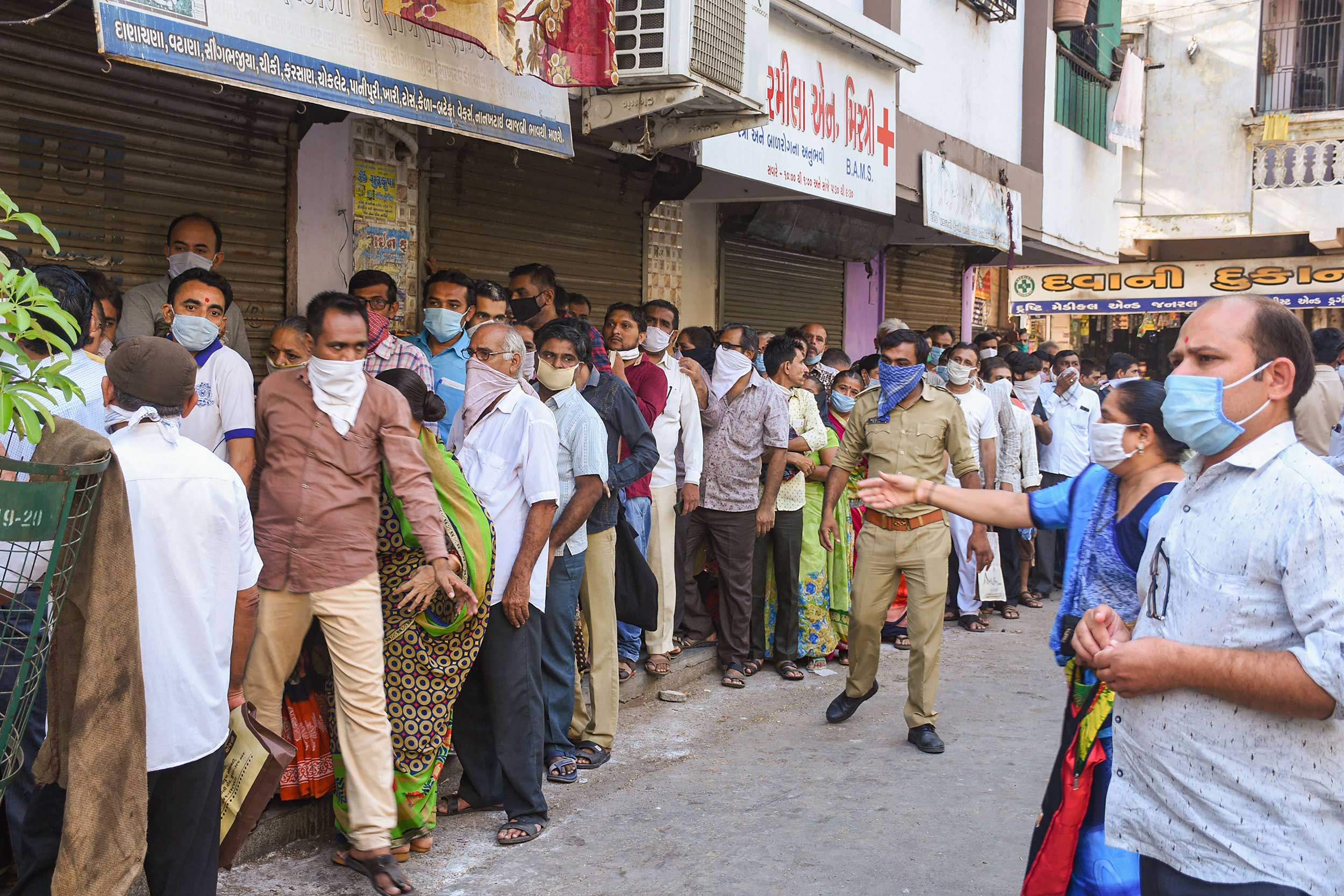 IGNORE SOCIAL DISTANCING: People stand in a queue to collect ration during the nationwide lockdown in Surat on Tuesday.