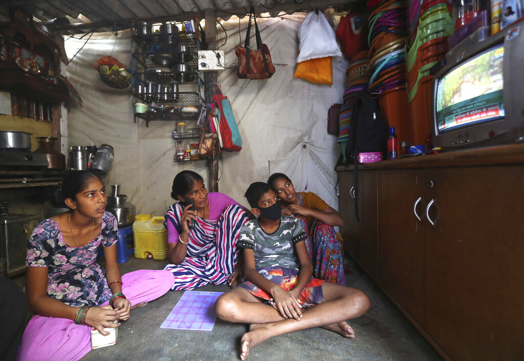 Mina watches news on the coronavirus along with her son and daughters Vaijayanti Ramesh and Guddi Ramesh in her one-room house