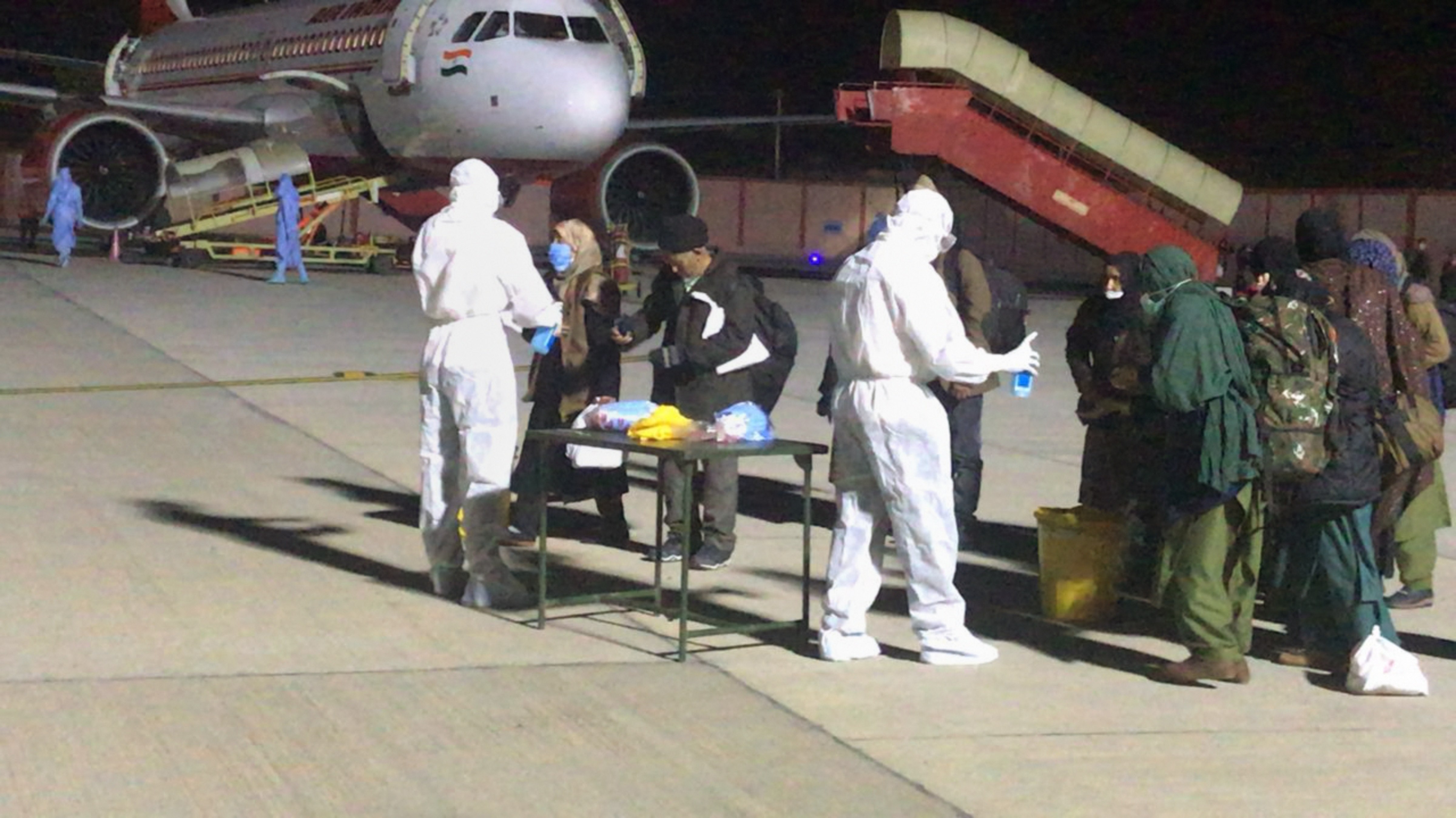 Medics examine evacuees from Iran upon their arrival at an airport in the wake of coronavirus pandemic