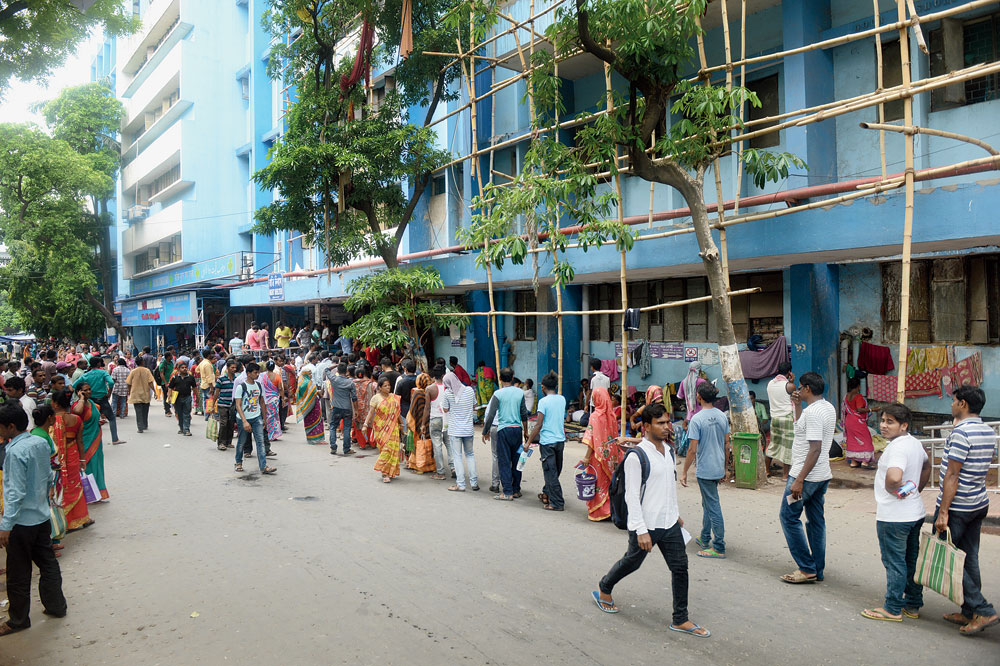 Visitors, some with food packets and water for patients undergoing treatment, queue up to enter the UNB Building of NRS hospital where the trouble had started after the death of a 75-year-old patient on Monday. Usually visitors have free access to the building as they come to deliver food and water for patients in the afternoon, on Wednesday security was tightened and only those having visitor’s pass were allowed in.