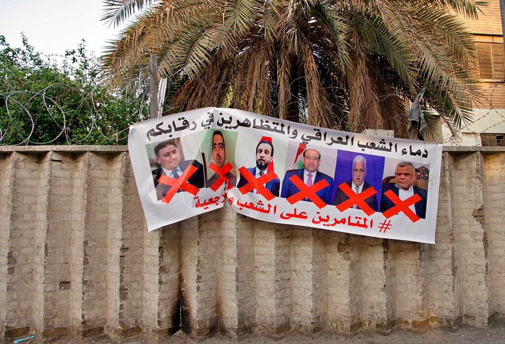 A poster with defaced pictures of Iraqi politicians and Arabic text that reads: "The blood of the protesters and the Iraqi people is on your necks, the conspirators on the people and the religious authority" near Tahrir Square in Baghdad on December 26