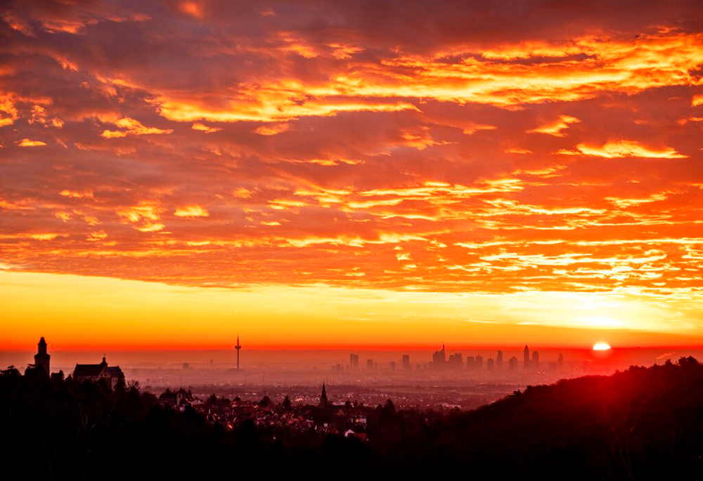 Colourful clouds over the city of Kronberg and the bank buildings in Frankfurt, Germany, as the sun rises on December 20